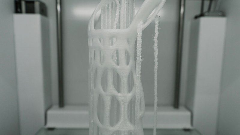 Een 3D-printer in actie met blauw filament op een verlichte werkplek