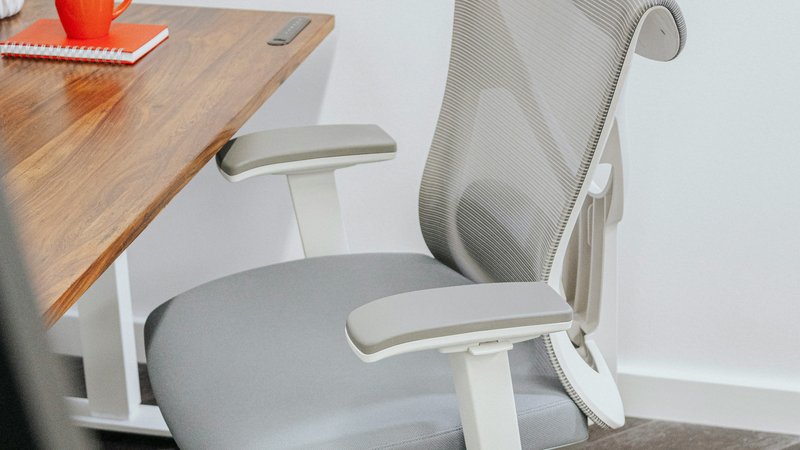Ergonomische bureaustoel met mesh rugleuning en verstelbare armleuningen bij een thuiswerkplek