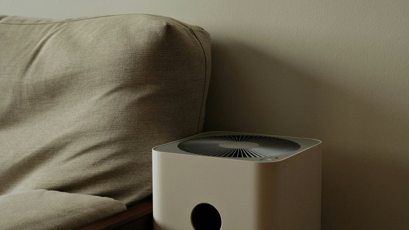 Compacte witte luchtreiniger in een nette woonkamer naast een plant