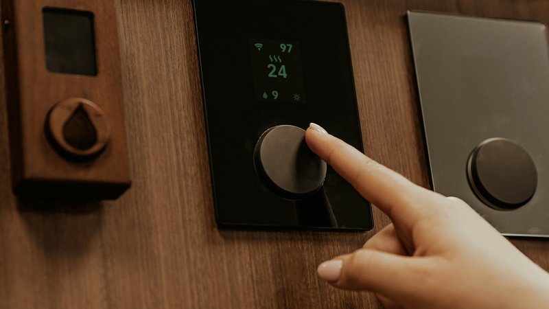 Slimme thermostaat aan de muur met temperatuurweergave en smartphone-app